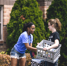 two female students carrying boxes at move-in