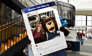 student posing for a photo with Shawn E. Bear at Orientation