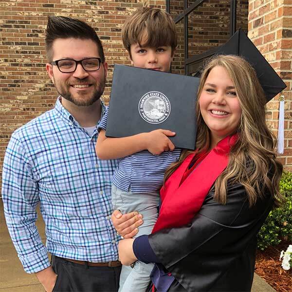 Keri Bentley in cap and gown with husband and child
