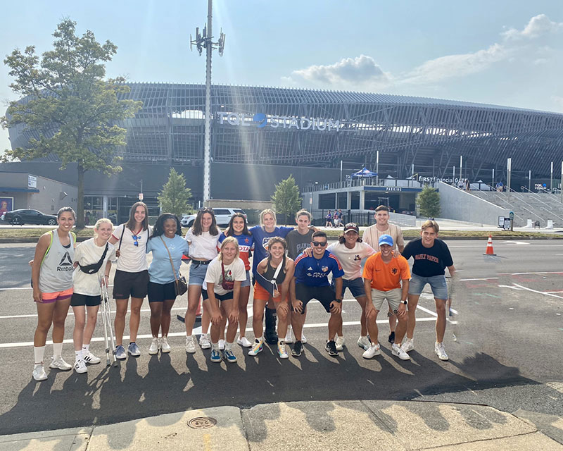 group photo of international students in front of soccer stadium