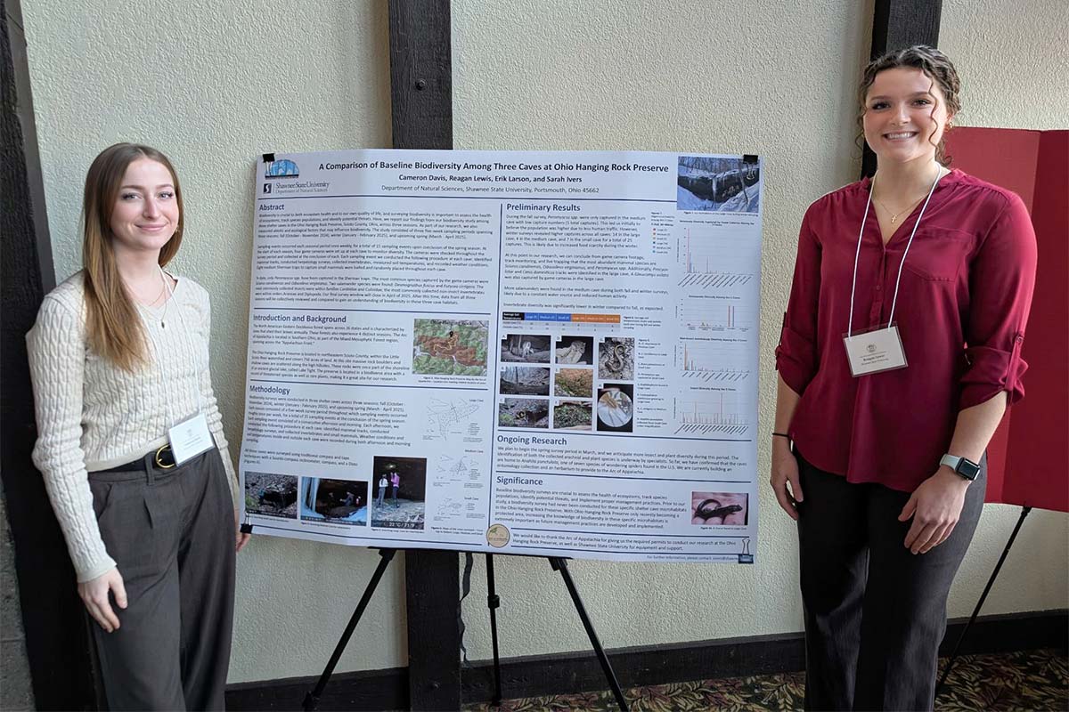 students posing by poster presentation