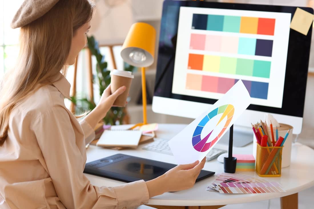 Female graphic designer working with color palette at table in office.