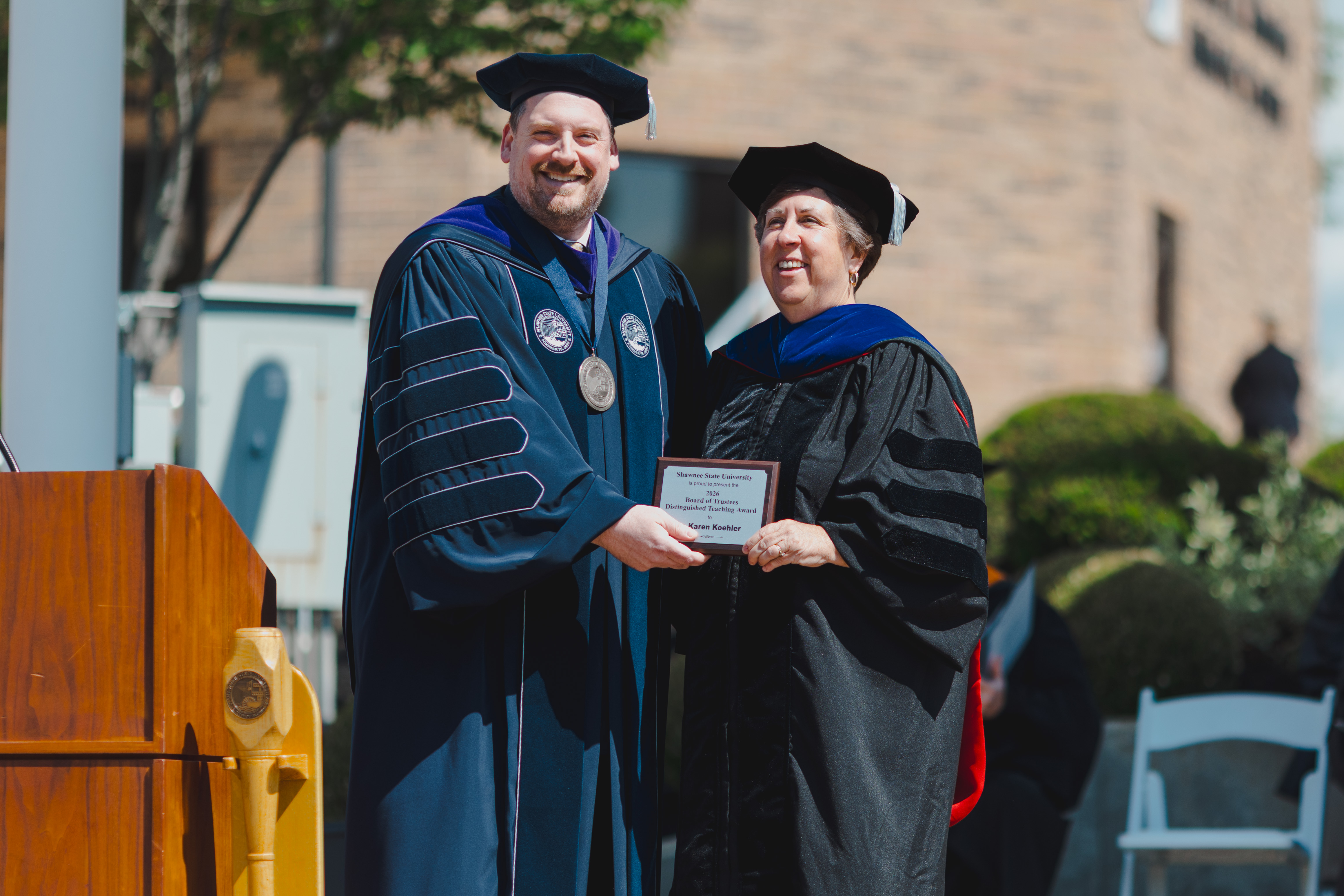 SSU President Eric Andrew Braun presents Dr. Karen Koehler with awards at commencement ceremony.
