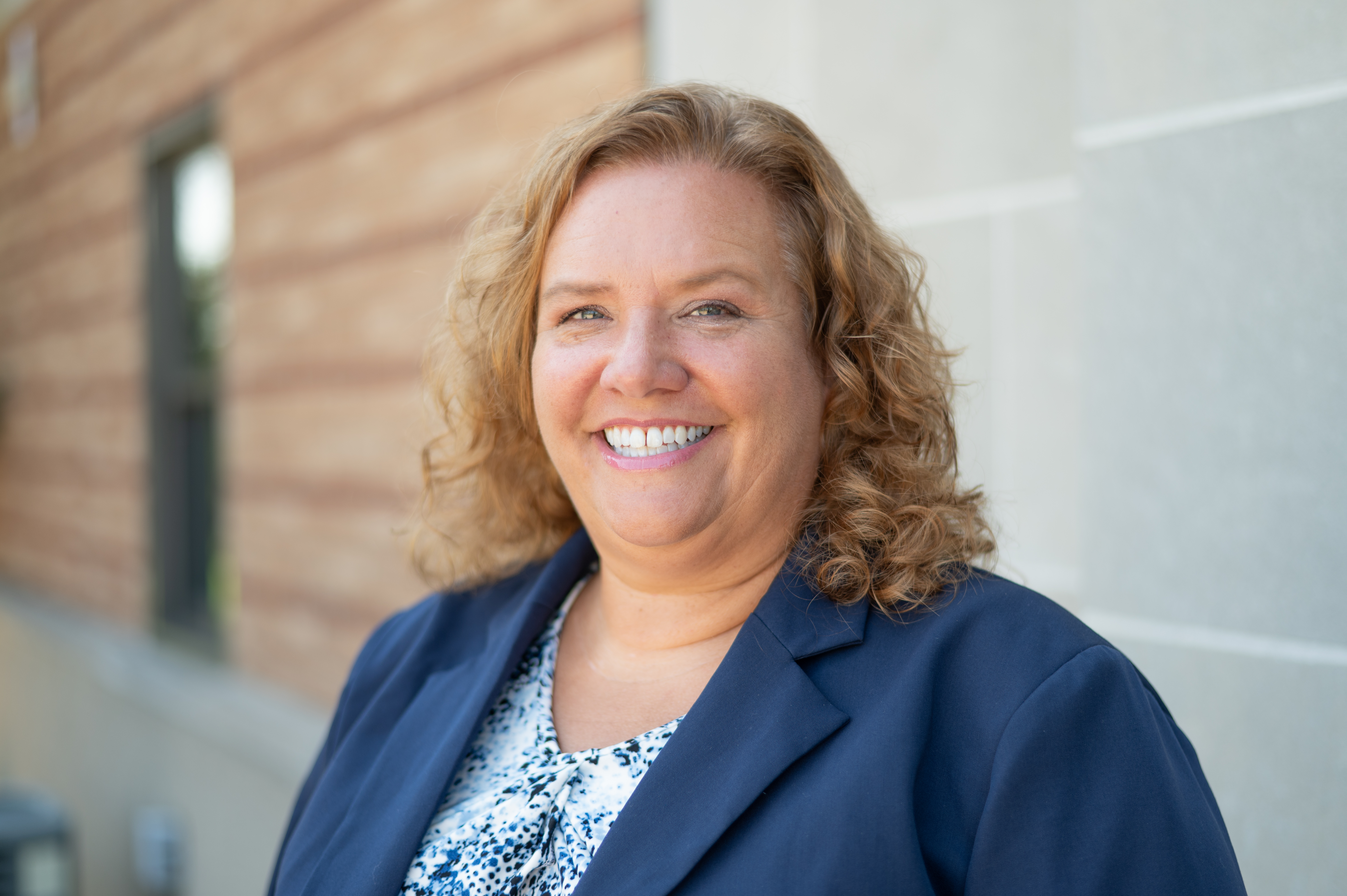 Portrait of Cindi Remy in blue blazer standing outside building