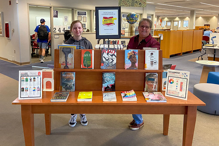 people posing with book display in library