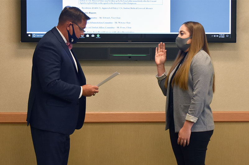 photo of man reciting oath and young woman raising right hand