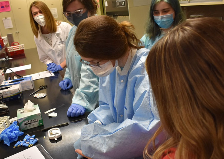 Students conduct a blood glucose test in lab