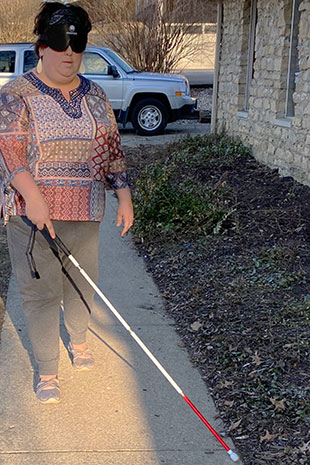 Woman using cane to navigate sidewalk