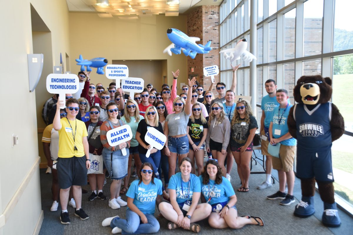 Group of new students at orientation holding celebratory signs