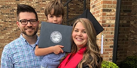 Keri Bentley in cap and gown with husband and child