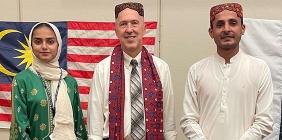 photo of students posing in front of flags