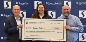 picture of three people holding large check