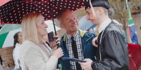 picture of student in cap and gown greeting his family