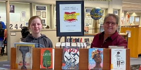 people posing with book display in library