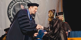 SSU President Eric Braun handing out diplomas during the Fall 2023 Commencement Ceremony