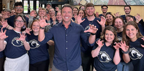 Group of Shawnee State students and a host Alex Boylan posing indoors with "Paws Up" hand gestures.