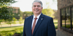 Portrait of man outside wearing a blue suit and striped tie