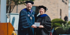 SSU President Eric Andrew Braun presents Dr. Karen Koehler with awards at commencement ceremony.
