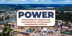 Aerial view of a riverfront city with a banner reading “POWER: Partnerships for Opportunity and Workforce and Economic Revitalization Initiative.”