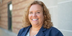 Portrait of Cindi Remy in blue blazer standing outside building